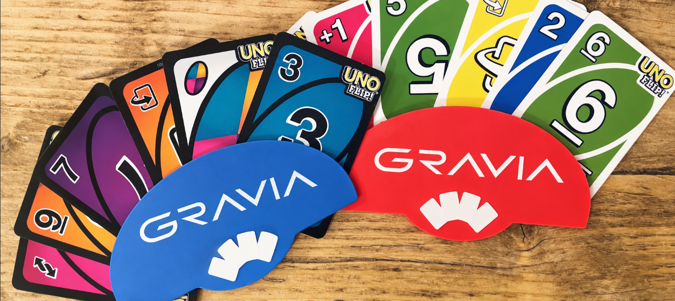 Blaue und rote GRAVIA-Kartenhalter mit Spielkarten auf einem Holztisch